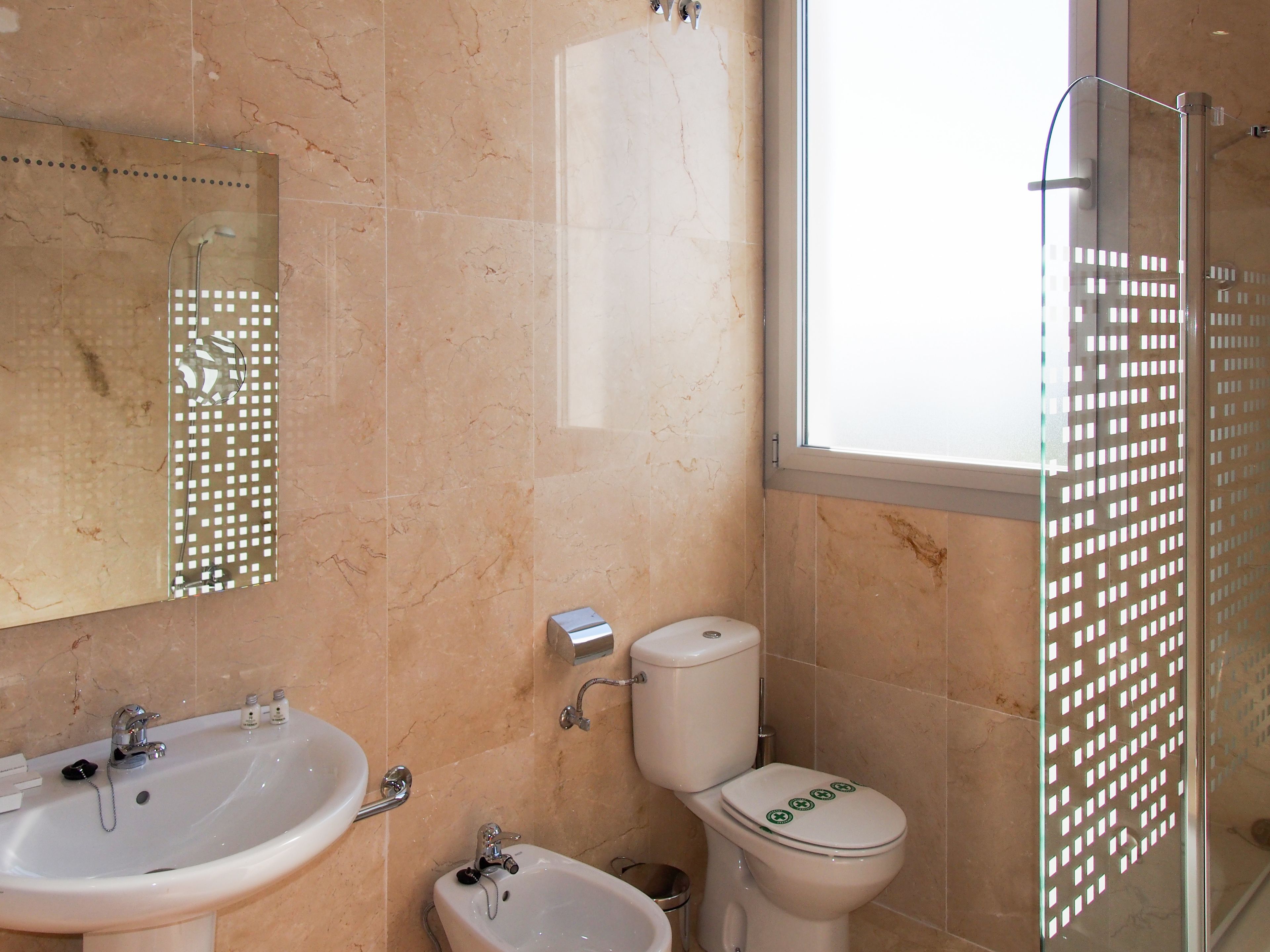 A bathroom with a sink, toilet, bidet, and a glass shower enclosure.
