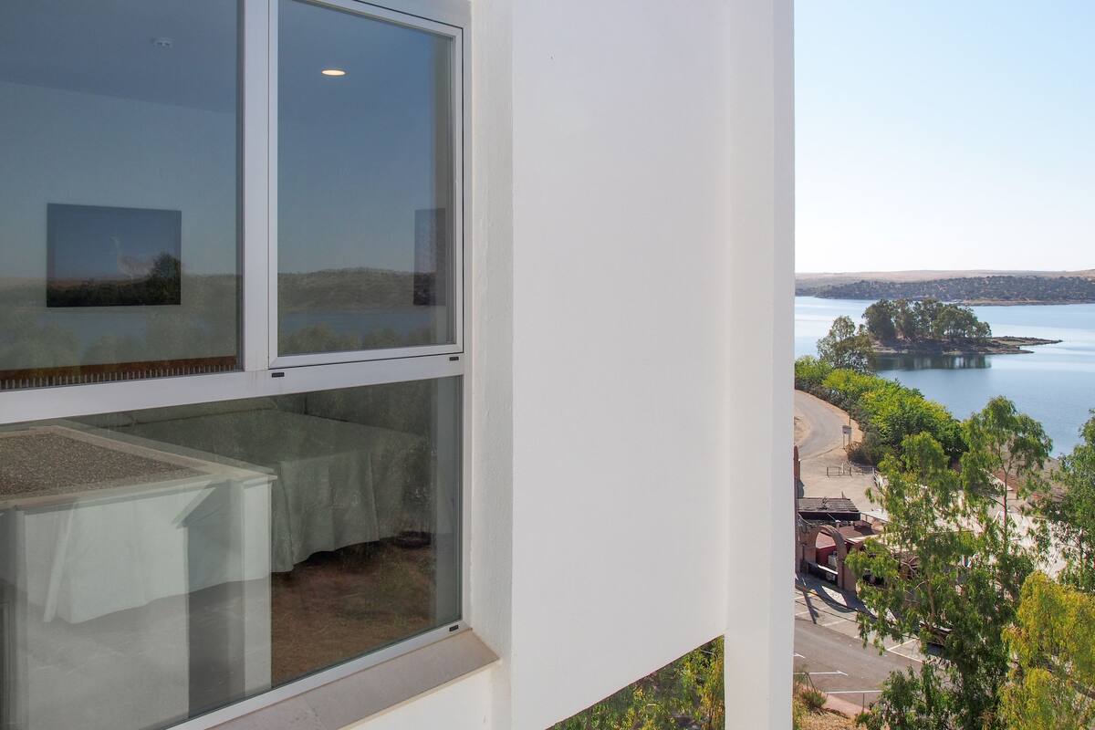 A room with a large window overlooking a lake and a small island.