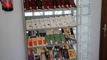 A book display rack in a room with a fire extinguisher on the wall and a tiled floor.