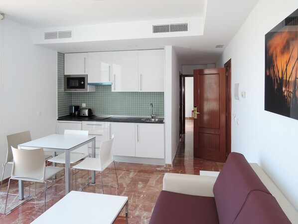 A compact living space with a kitchenette, a dining area with a table and chairs, and a sofa.