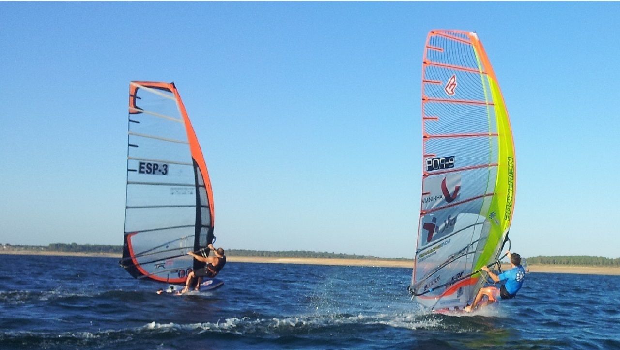 Two windsurfing individuals on a body of water.