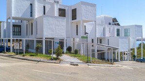A modern white building with a flat roof, large windows, and a covered outdoor area. - Apartamentos Embalse de Orellana (Orellana la Vieja)