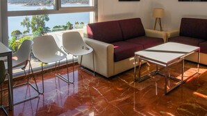 A modern living room with a sofa, two chairs, a coffee table, and a view of a lake. - Apartamentos Embalse de Orellana (Orellana la Vieja)