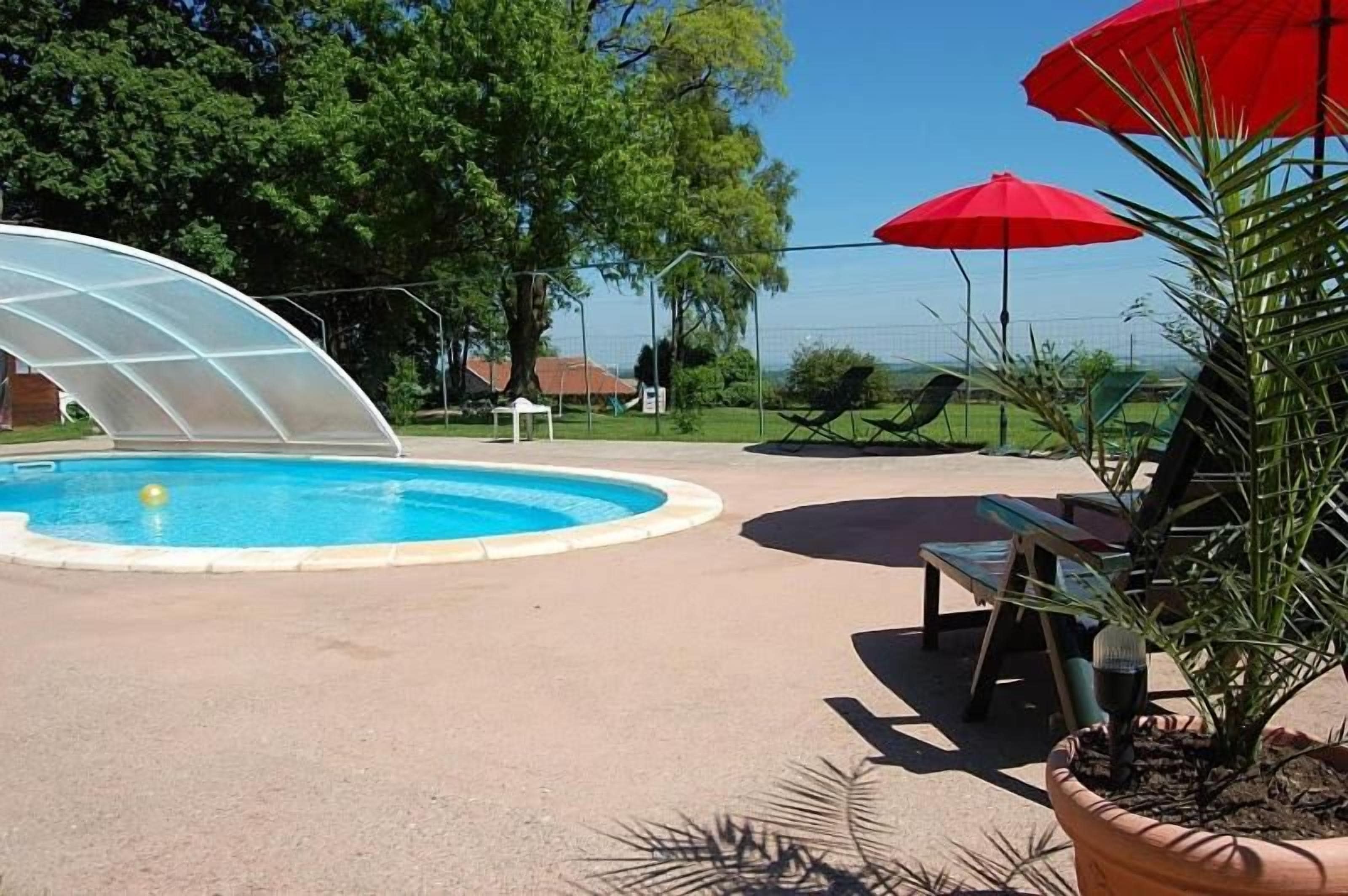 Een zwembad met glazen omheining, omringd door ligbedden en rode parasols.