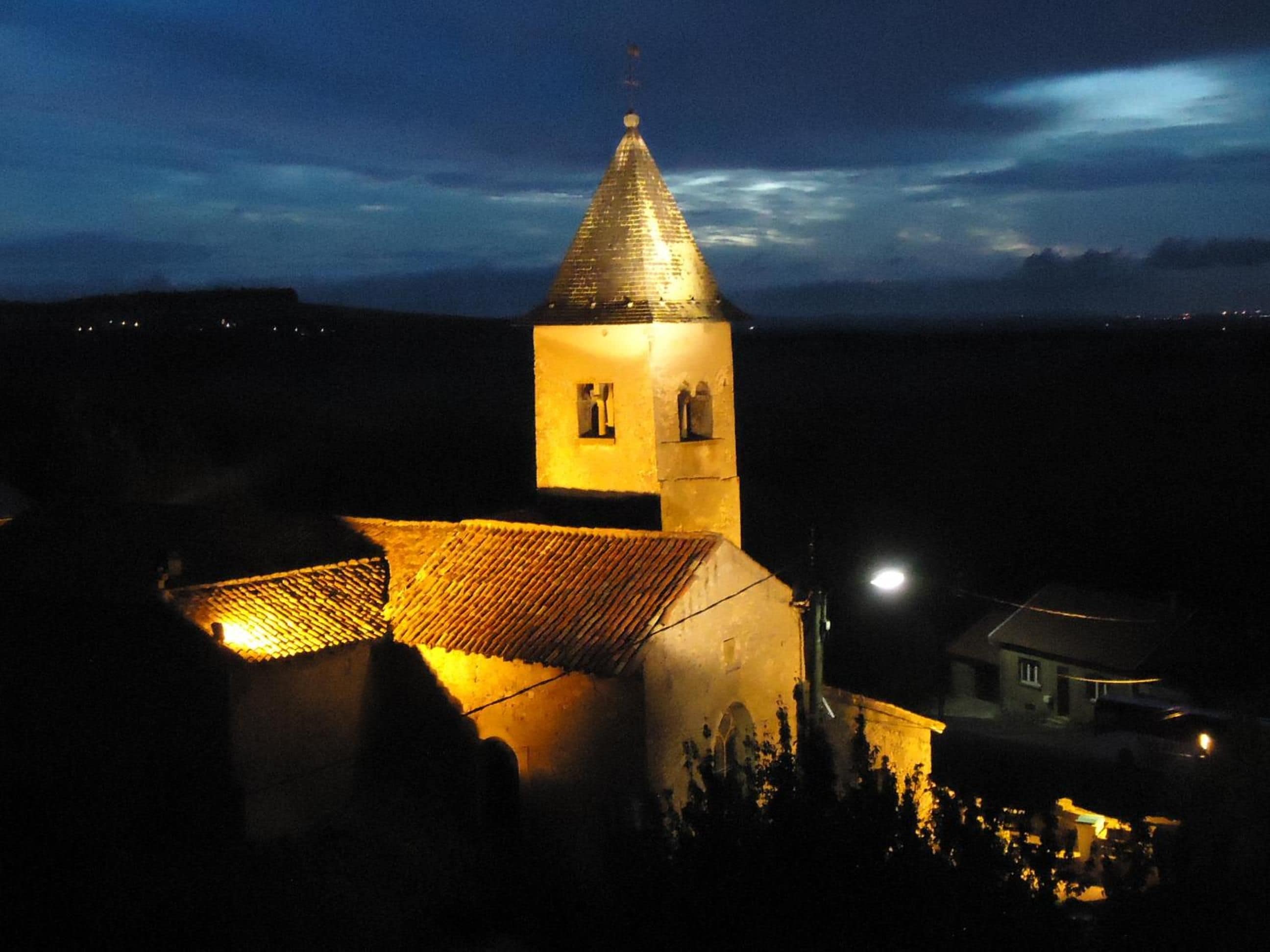 A church with a bell tower, a tiled roof, and a small window.