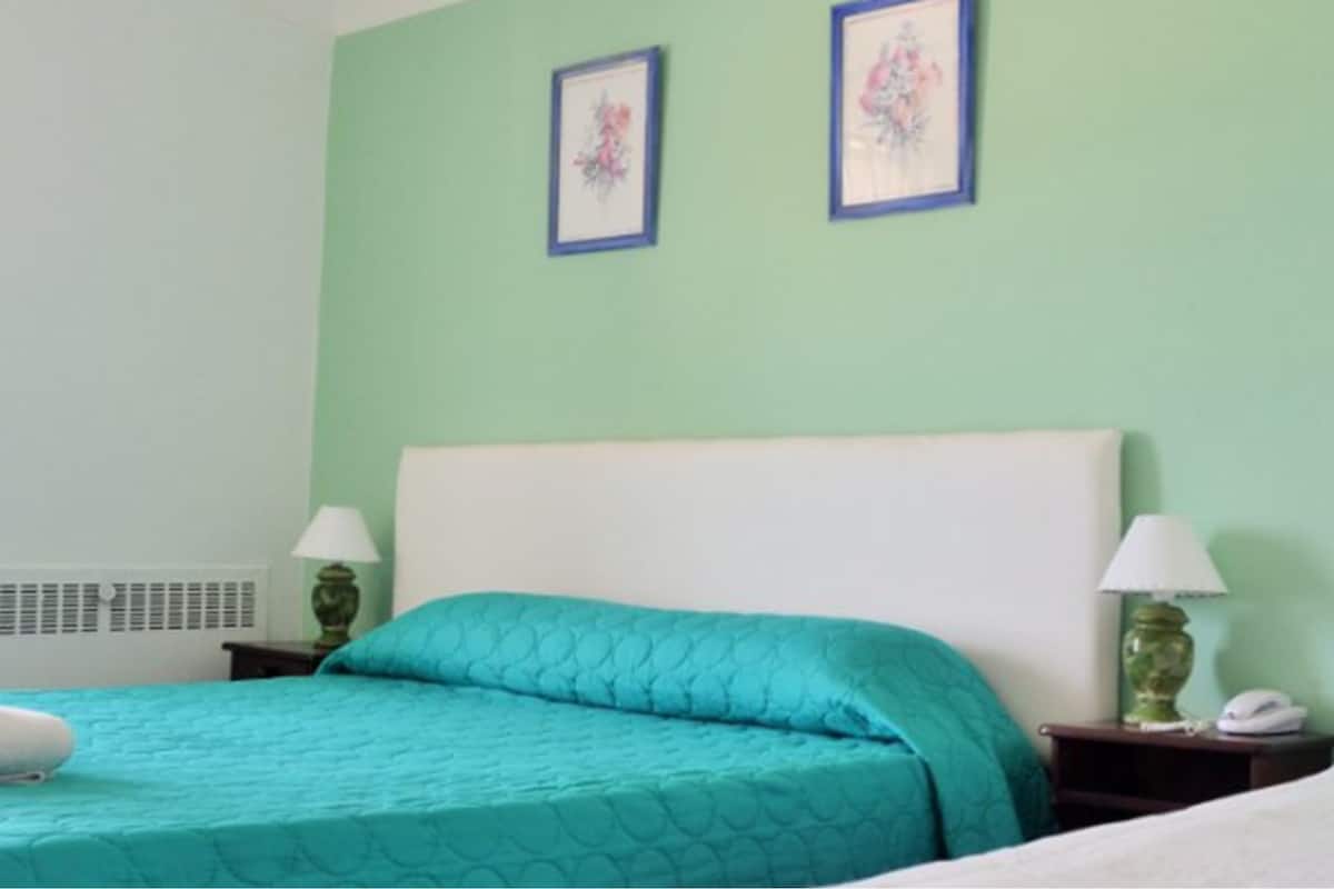 Een hotelkamer met een bed, twee nachtkastjes en twee wandlampen.