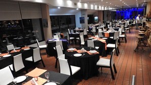 A banquet hall with round tables, white chairs, and black tablecloths.