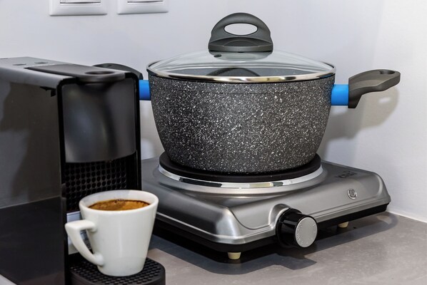 A kitchen with a coffee maker, a pot on a portable stove, and a white mug. - Amara Solar Living (Chania)