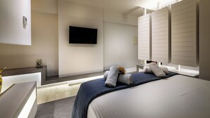 Una habitación de hotel moderna con una cama grande, un televisor de pantalla plana montado en la pared y un armario empotrado con puertas correderas.