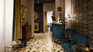 A modern interior with a geometric patterned floor, a blue velvet sofa, and a bar area. - Mi Hotel Home (Rome)