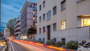 A multi-story building with a no parking sign, a visible entrance, and a street with light trails indicating traffic. - Mi Hotel Home (Rome)