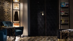 A dark room with a large door, a bookshelf with books, and a patterned wall. - Mi Hotel Home (Rome)