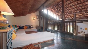 A spacious room with a large bed, wooden furniture, and a thatched roof ceiling. - casa gaiolas (Ubatuba)