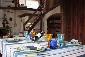 A dining table set with plates, glasses, and a wine bottle. - casa gaiolas (Ubatuba)
