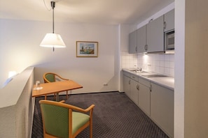 A compact kitchen with a dining area, a hanging light fixture, and a framed picture on the wall. - Hotel Rostock West im Kritzmow Park (Kritzmow)