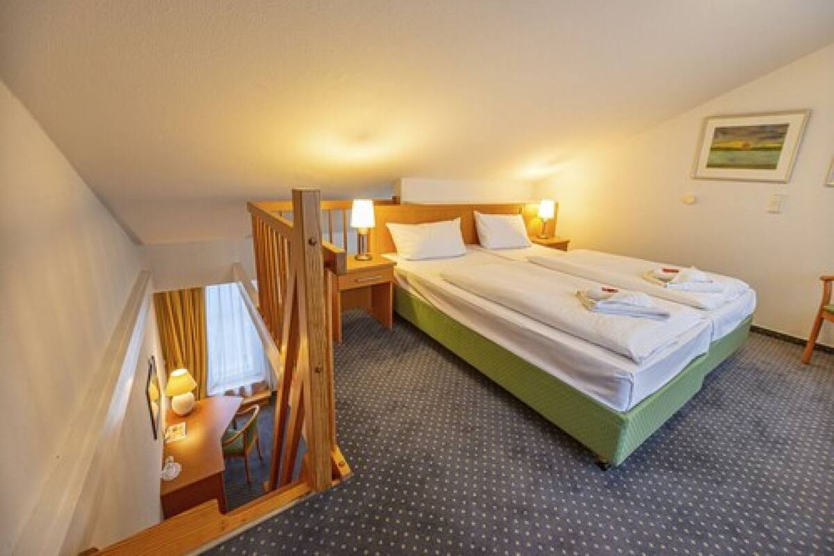 A hotel room with a single bed, a desk, and a chair.