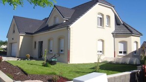 Une maison à deux étages avec un toit en pente, une pelouse devant et une porte de garage bien visible.