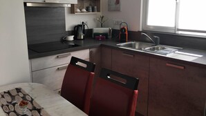 Une cuisine compacte équipée d’un évier, d’une cuisinière et d’un coin repas avec une table et des chaises.