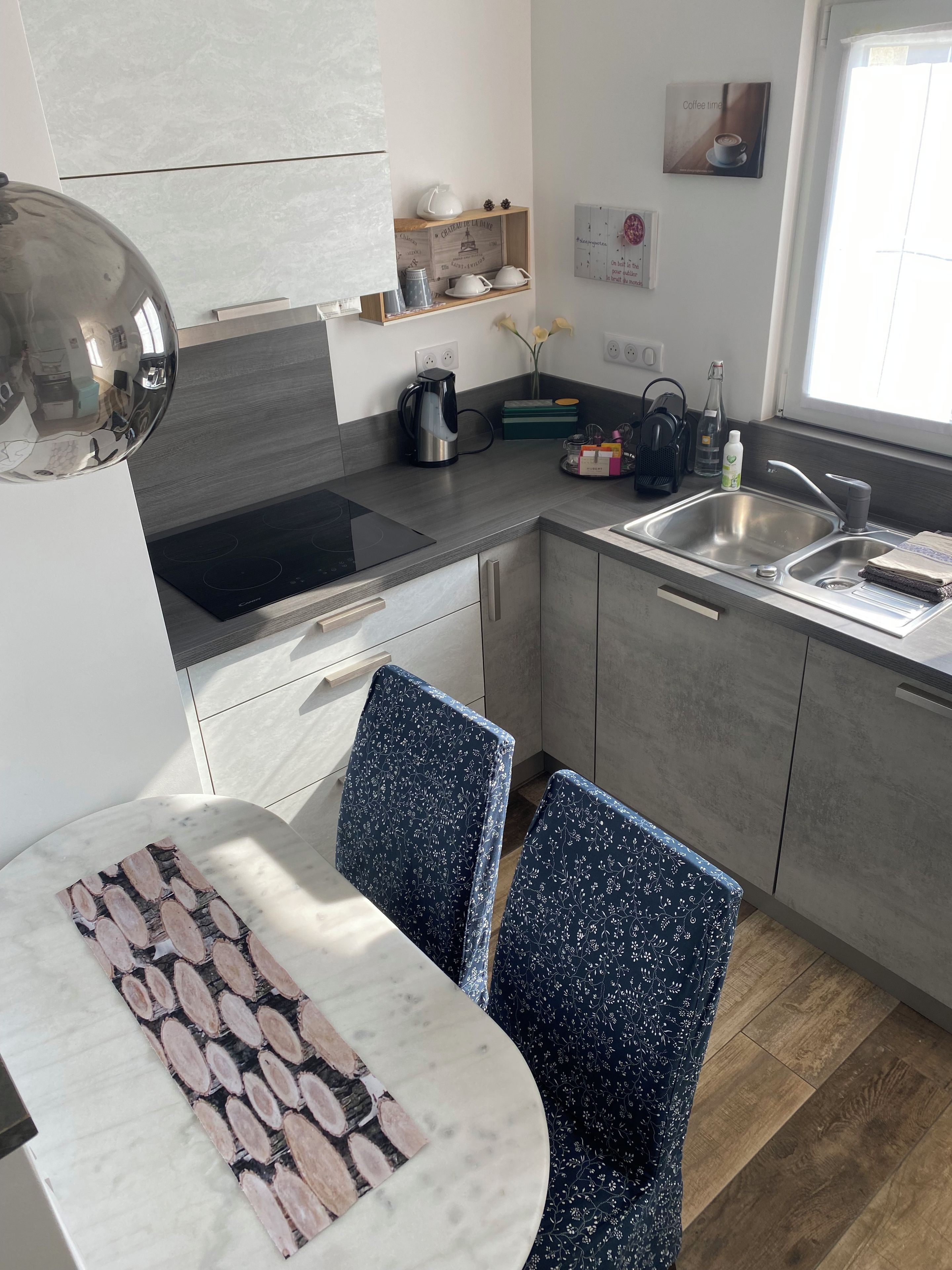 Cocina moderna con estufa integrada, pileta y comedor con mesa de mármol y sillas estampadas.