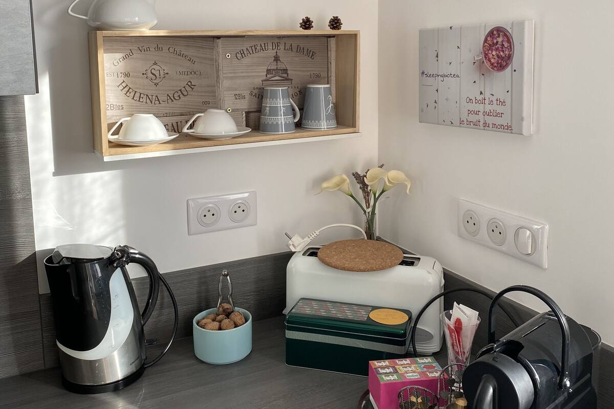 A kitchen with a coffee machine, a toaster, a kettle, and a shelf with decorative items.