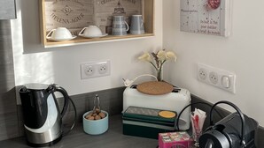 Une cuisine équipée d’une machine à café, d’un grille-pain, d’une bouilloire et d’une étagère où sont disposés des objets décoratifs.