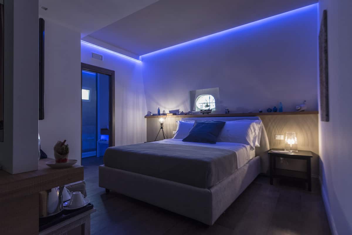 Ein modernes Hotelzimmer mit einem großen Bett, Nachttischen, einem kleinen Fernseher und stimmungsvoller Beleuchtung.