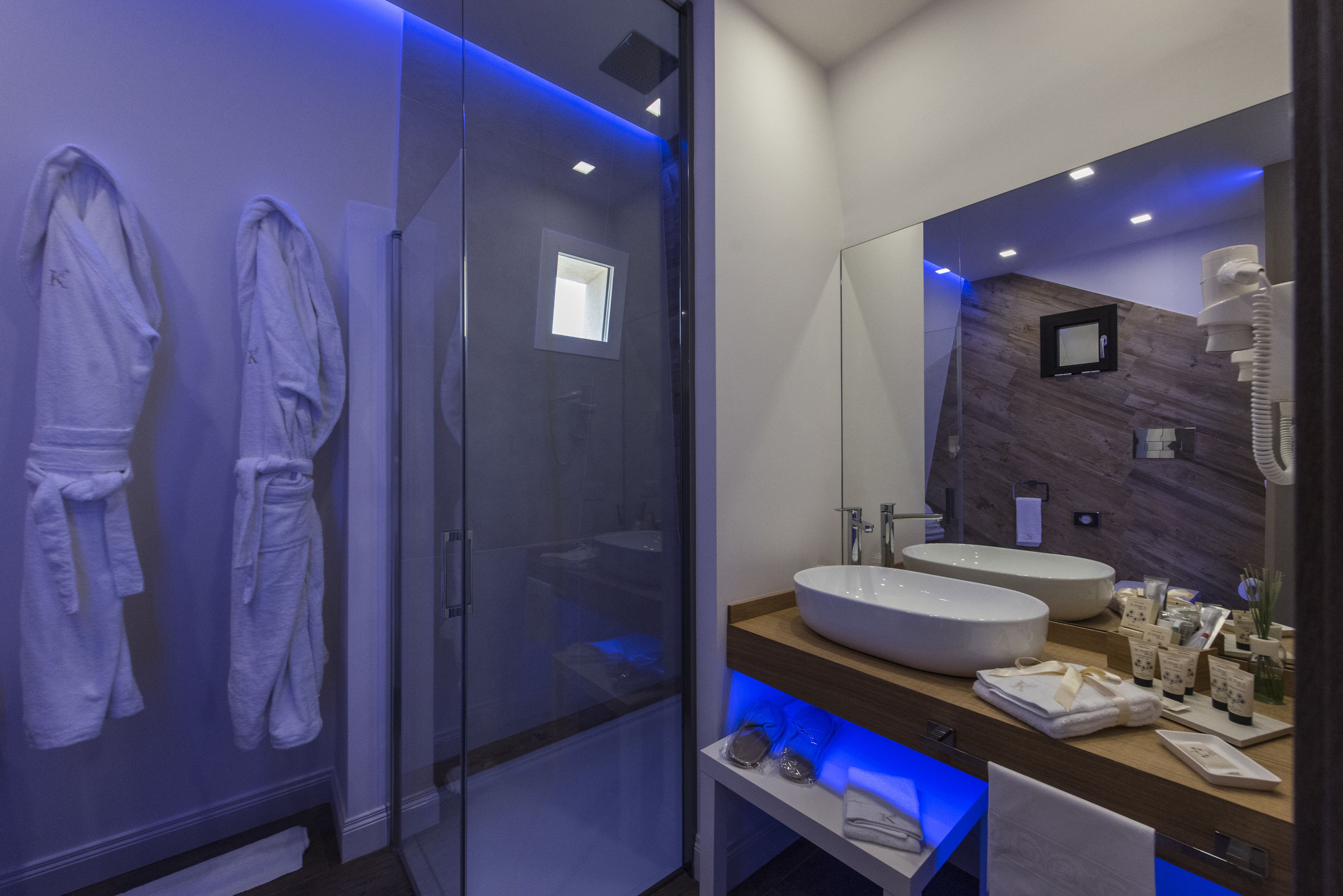Ein modernes Badezimmer mit Duschkabine aus Glas, zwei Waschbecken und einem Waschtisch mit Toilettenartikeln.