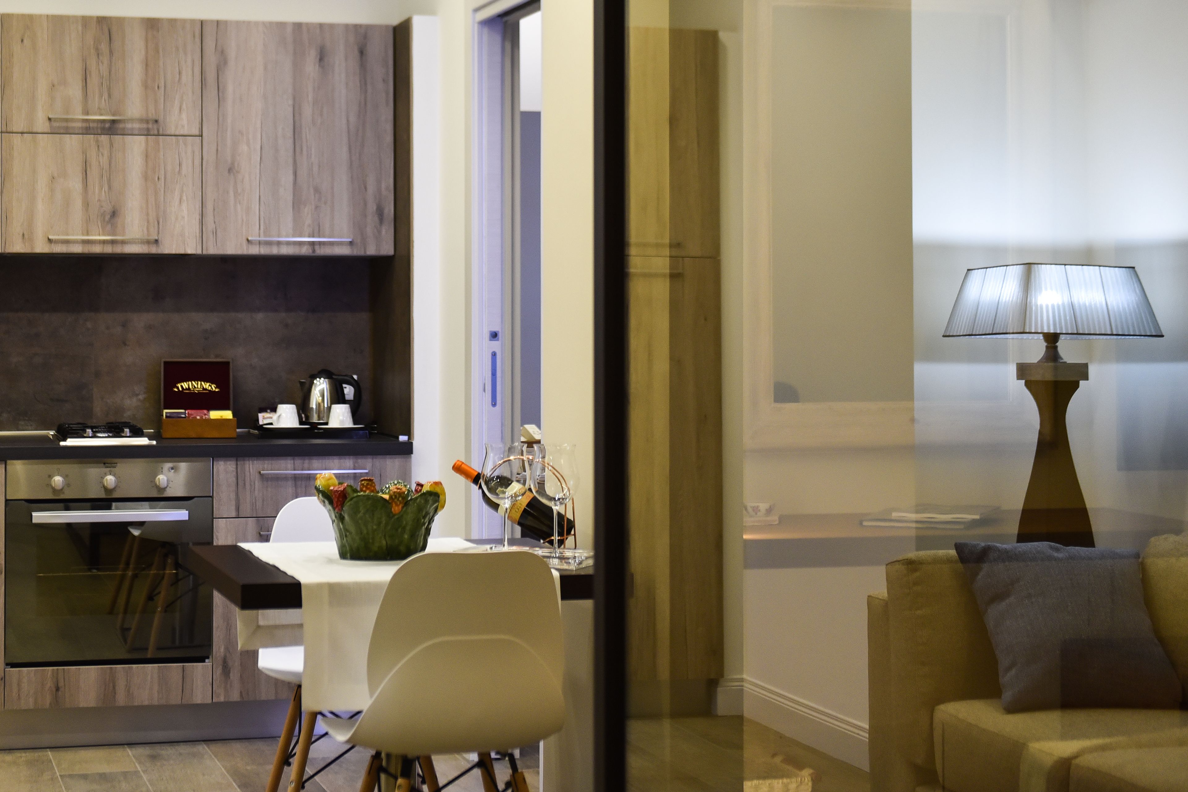 Een moderne keuken met houten kasten, een eettafel met stoelen en een bank in de woonkamer.