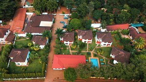 An aerial view of a residential area with houses, a swimming pool, and a red-roofed building. - Keys Hotel Mbokomu Branch (Moshi)