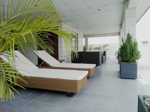 Un área de descanso moderna con sillones de mimbre y una jardinera central con follaje.