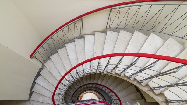 A spiral staircase with a red handrail and metal balusters. - Visarno Arena Apartment (Florence)