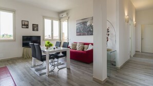 A modern living room with a dining area, a red sofa, and a TV. - Visarno Arena Apartment (Florence)