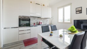 A modern kitchen with white cabinets, a built-in oven, and a dining area with a white table and chairs. - Visarno Arena Apartment (Florence)