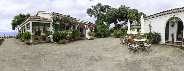 A courtyard with stone flooring, outdoor seating, and potted plants.