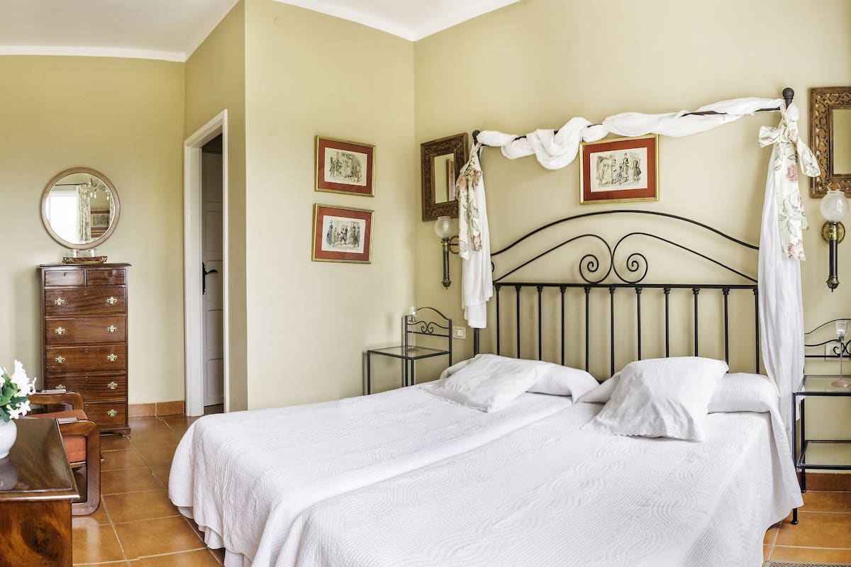 Une chambre avec deux lits, une commode, un miroir et des tableaux encadrés accrochés au mur.