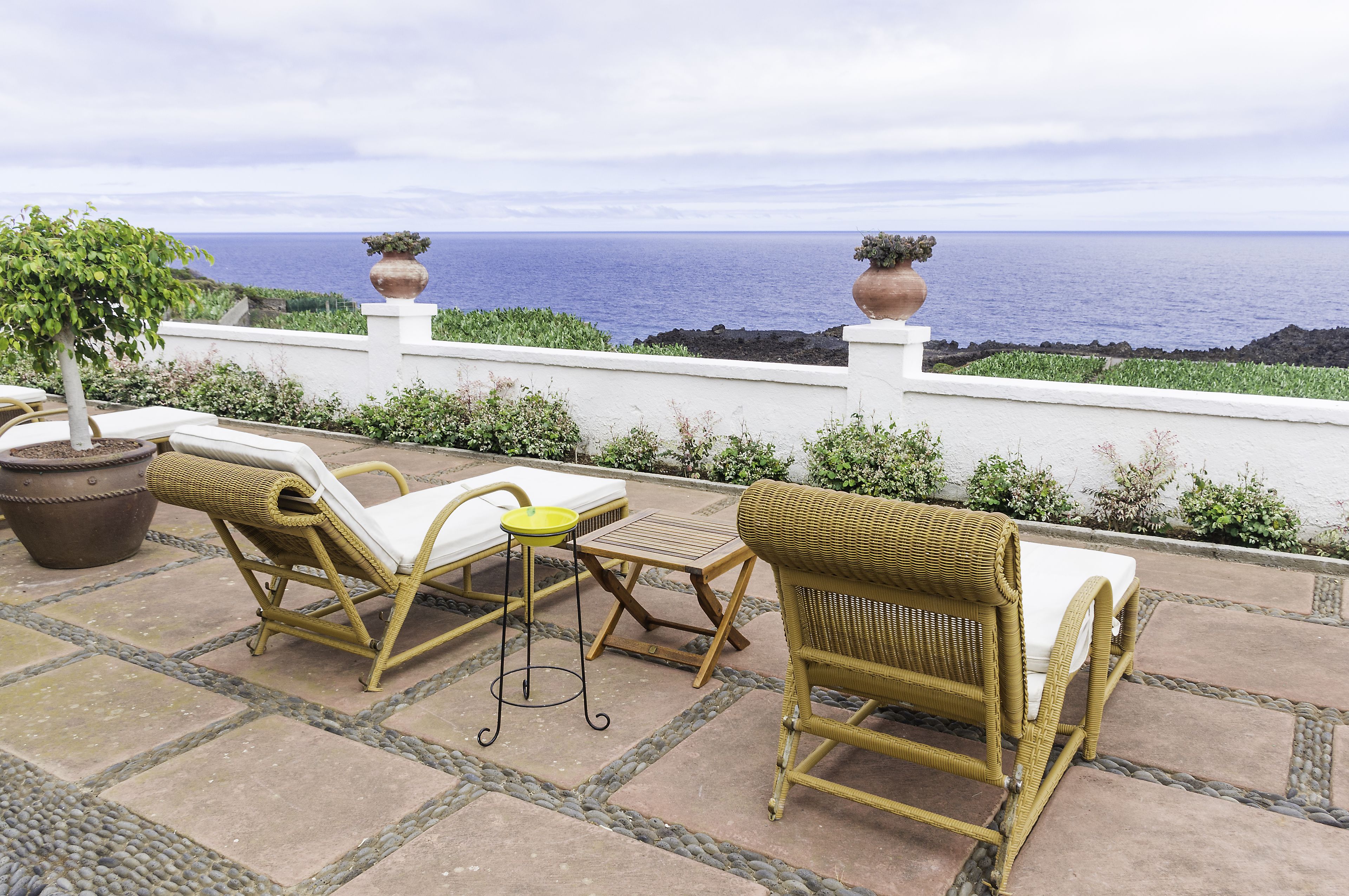 Un patio con muebles de mimbre y vista al océano.