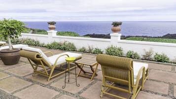 Un patio con muebles de mimbre y vista al océano.