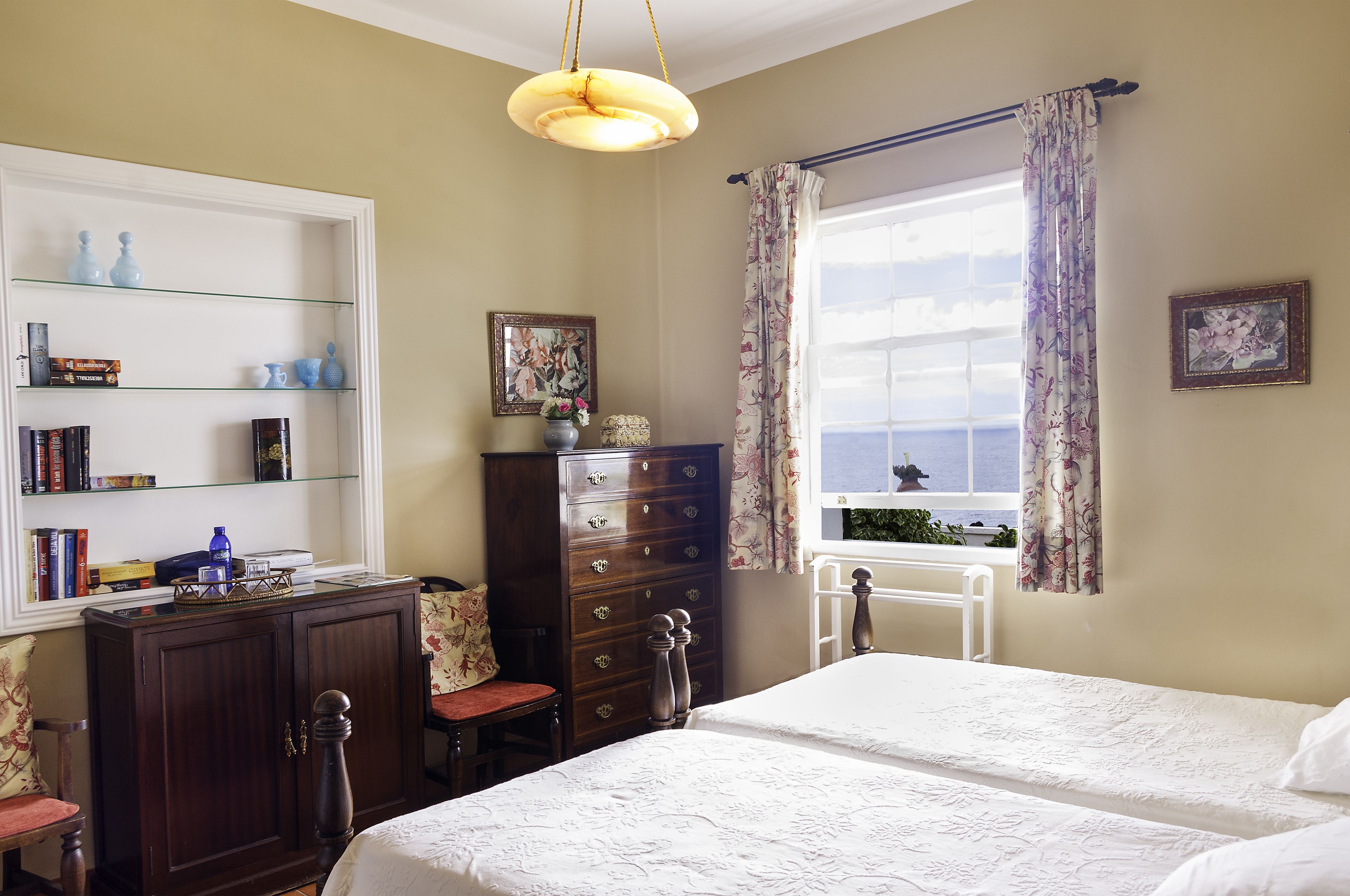 Une chambre à coucher avec un lit, une commode et une fenêtre avec des rideaux.