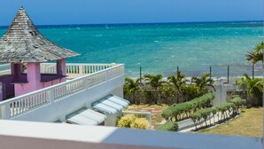A hotel with a pink building, a white balcony, and a view of the ocean. - Seacrest Beach Hotel (St. Ann's Bay)