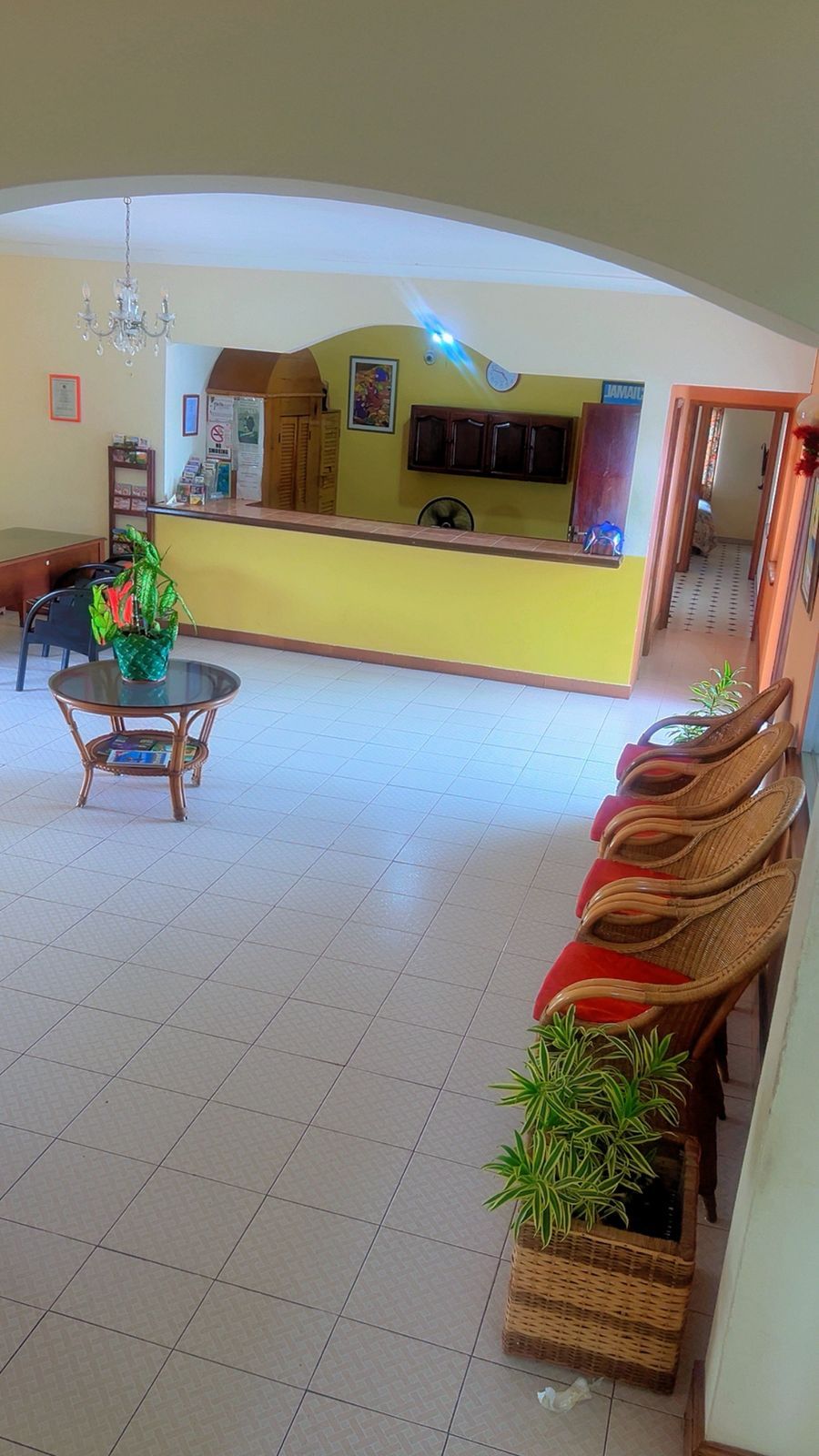 A spacious living area with a central island, a dining table with chairs, and a seating area with wicker furniture.