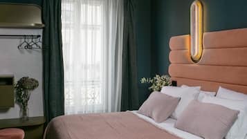 Een netjes opgemaakt bed met een hoofdeinde met ingebouwde verlichting. Er is een raam met dunne gordijnen en uitzicht op het omliggende landschap.