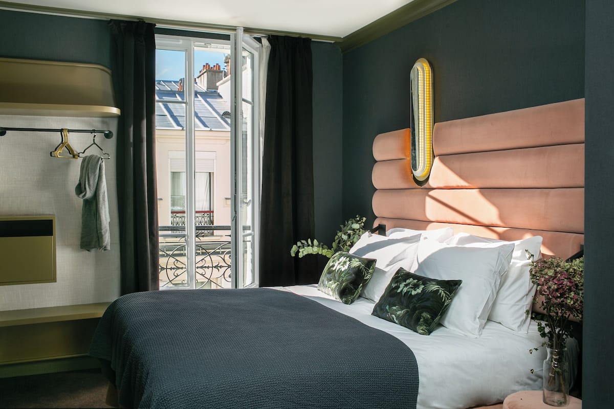 Habitación de hotel con cama, banca, calefacción, ventana y vista al exterior.