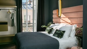 A hotel room with a bed, a bench, a window, and a view of the outside. - La Planque Hôtel (Paris)
