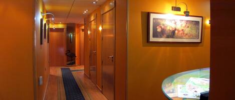 A hotel hallway with wooden doors, a carpeted floor, and a glass table with a menu.