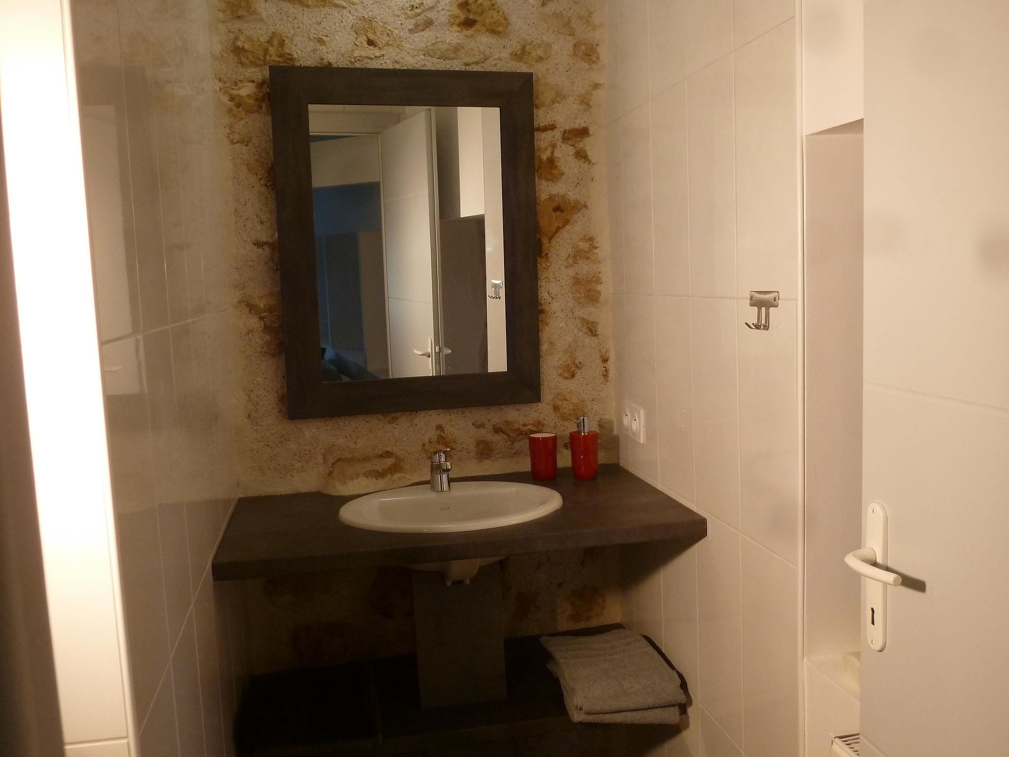 Un bagno con lavandino, specchio e porta asciugamani.