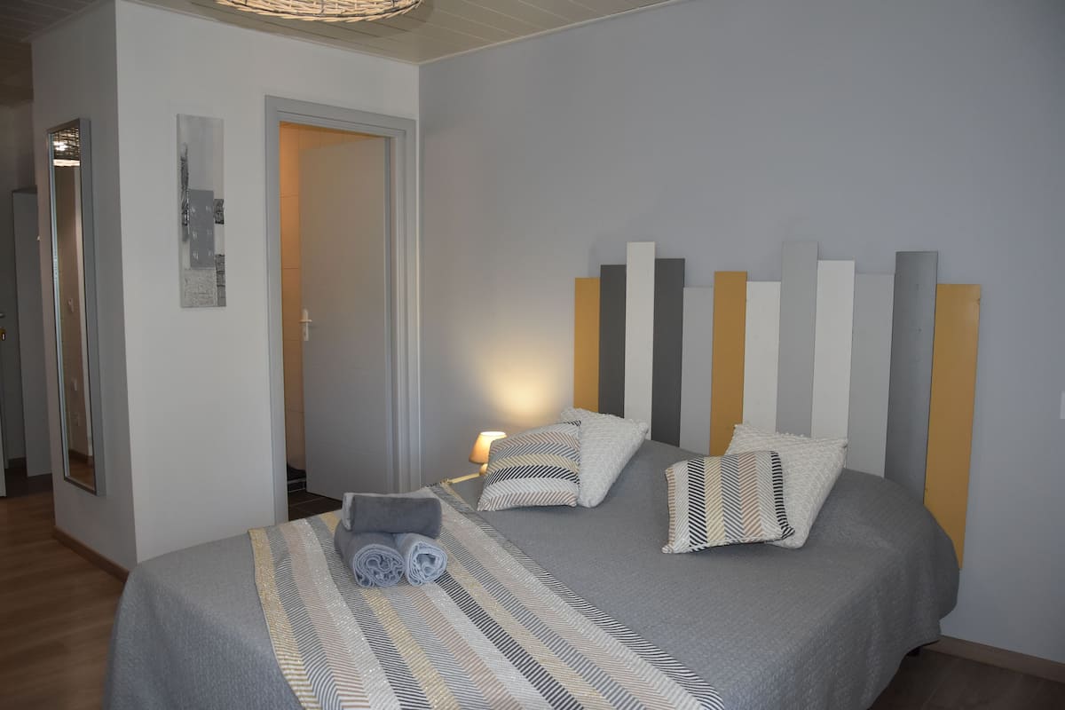 Une chambre bien rangée, avec un lit, des oreillers et une serviette enroulée.