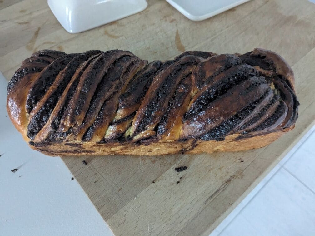 Una hogaza de pan con un diseño trenzado sobre una tabla de madera.
