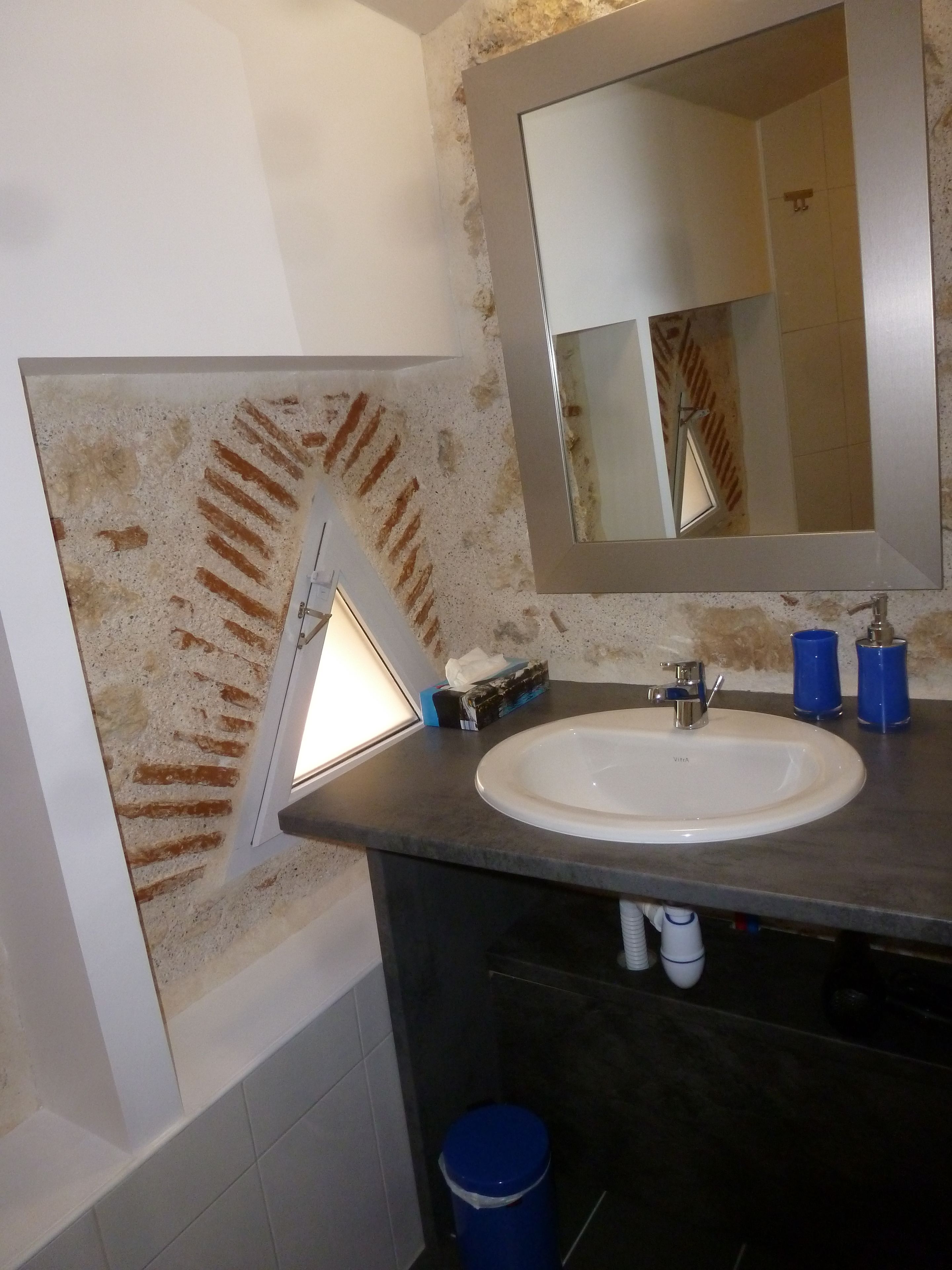 Une salle de bain avec un lavabo blanc, un miroir et un distributeur de serviettes.
