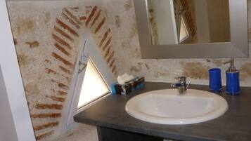 Une salle de bain avec un lavabo blanc, un miroir et un distributeur de serviettes.