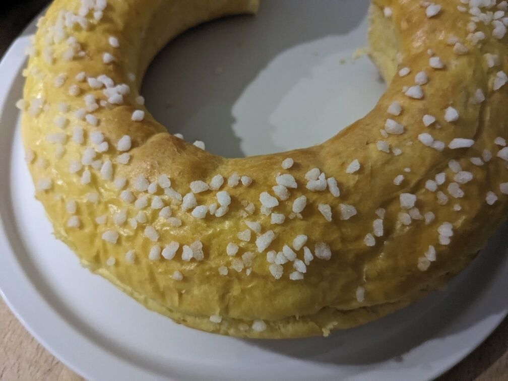 Un pastelito redondo con azúcar blanca granulada sobre un plato blanco.